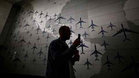 A silhouetted figure stands in front of a huge map of the Americas covered in outlines of blue aircraft of various sizes